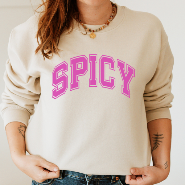 Person wearing a beige sweatshirt with 'SPICY' in pink text on a plain background