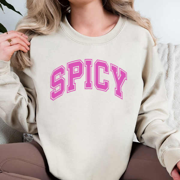 Person wearing a beige sweatshirt with 'SPICY' in pink text
