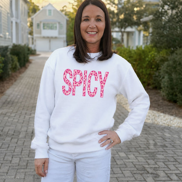 Woman wearing a white Spicy leopard print sweatshirt and white jeans outdoors