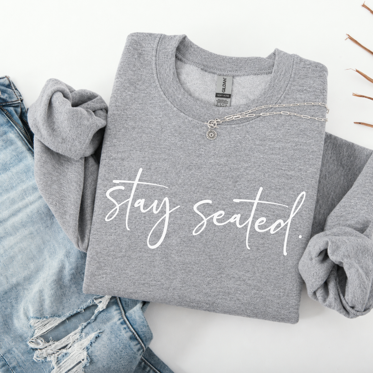 Folded gray sweatshirt with 'stay seated' text on a white background