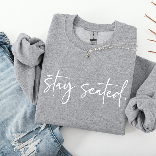 Folded gray sweatshirt with 'stay seated' text on a white background