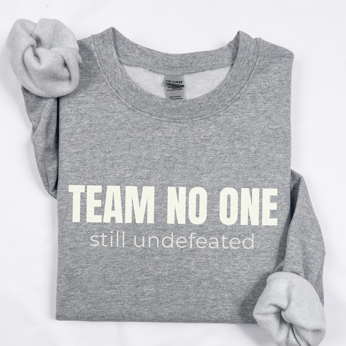 Gray sweatshirt with 'Team No One still undefeated' text on a white background