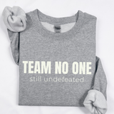 Gray sweatshirt with 'Team No One still undefeated' text on a white background