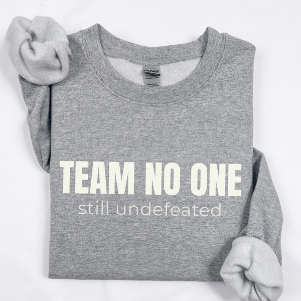 Gray sweatshirt with 'Team No One still undefeated' text on a white background