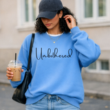 Woman wearing a blue sweatshirt with 'Unbothered' text, holding a drink.