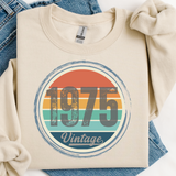 Beige sweatshirt with '1975 Vintage' design on a blue denim background