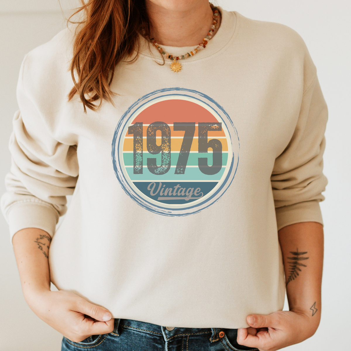 Beige sweatshirt with '1975 Vintage' graphic design worn by a person.