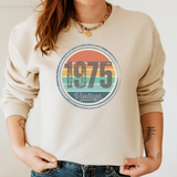 Beige sweatshirt with '1975 Vintage' graphic design worn by a person.