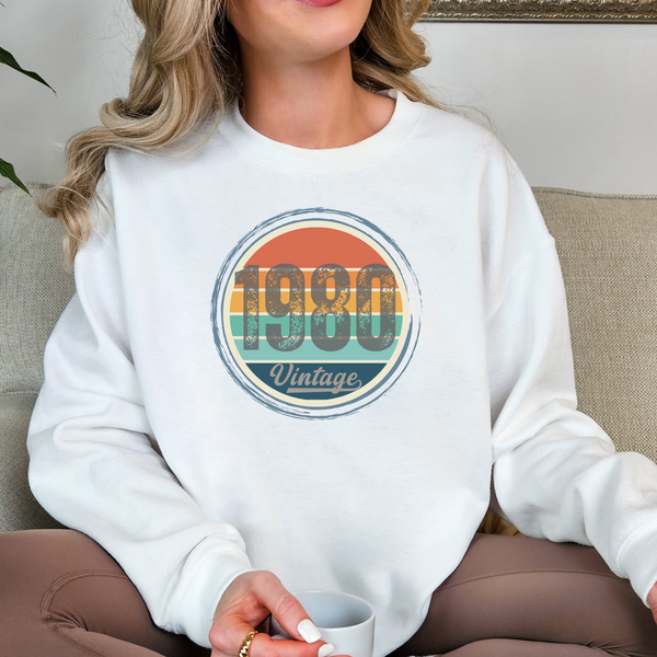Person wearing a white sweatshirt with '1980 Vintage' design, holding a mug.