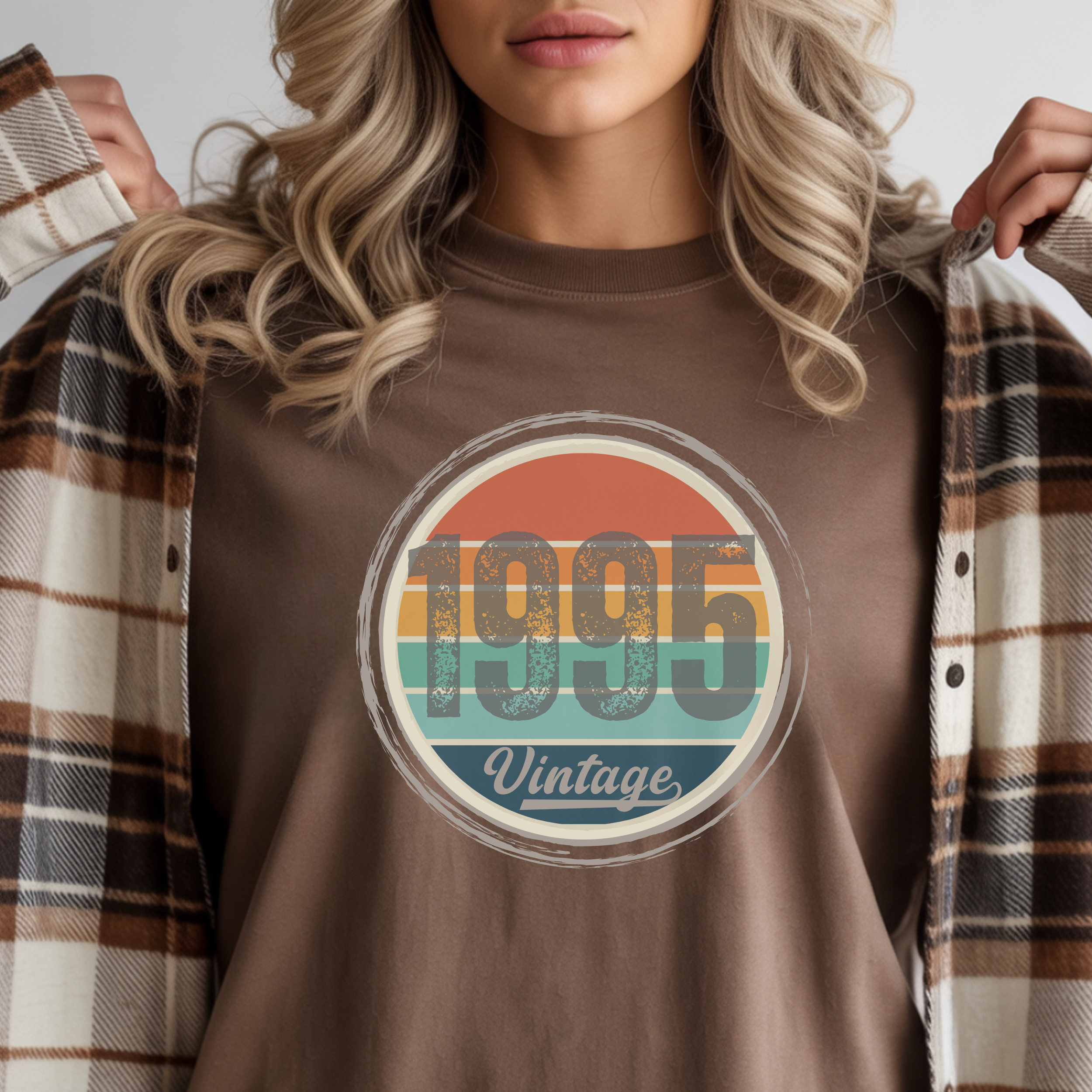 Person wearing a brown t-shirt with '1995 Vintage' design, holding a plaid jacket.
