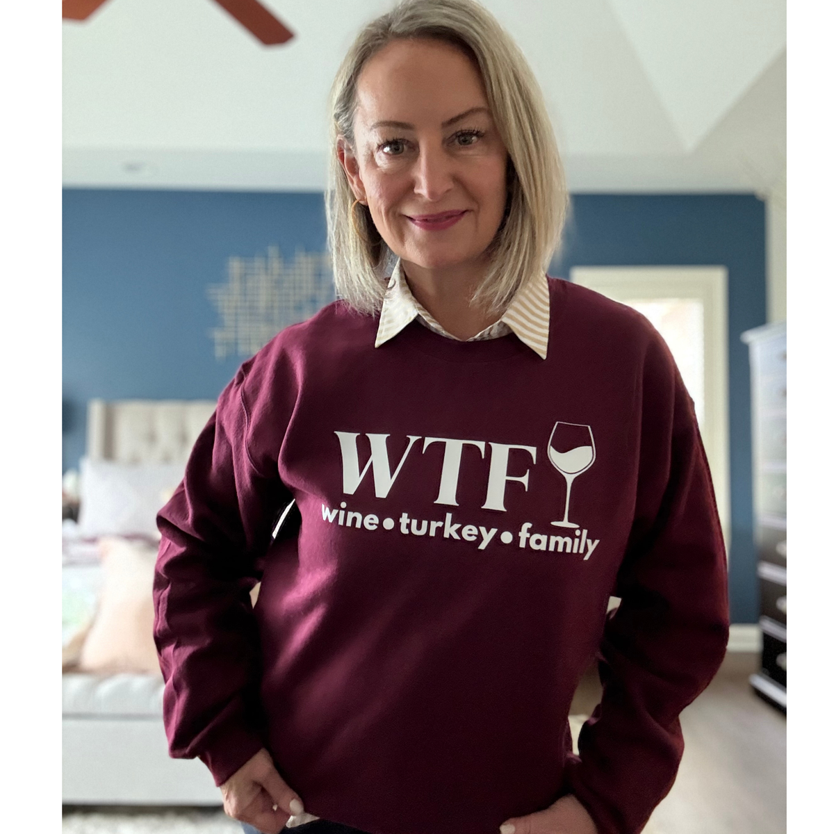 Woman wearing a maroon sweatshirt with 'WTF wine turkey family' text in a room.