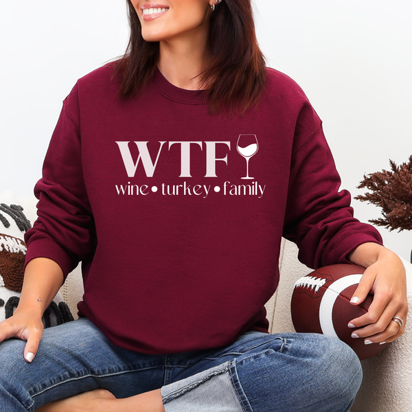 Person wearing a maroon sweatshirt with 'WTF wine turkey family' text, holding a football.