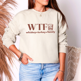 Person wearing a light-colored sweatshirt with 'WTF whiskey turkey family' text and graphic.