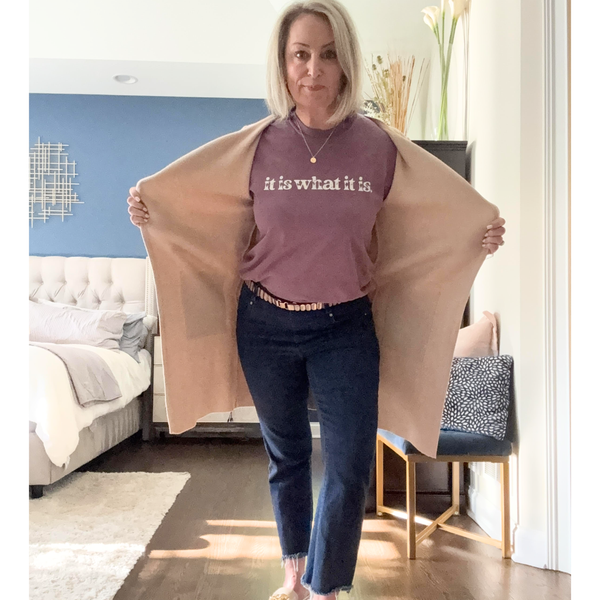Woman wearing a purple tee with text in a living room that says "it is what it is"