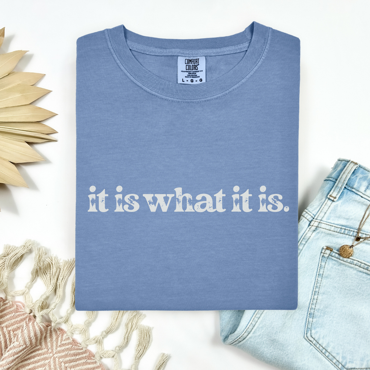 Blue t-shirt with 'it is what it is' text on a white background