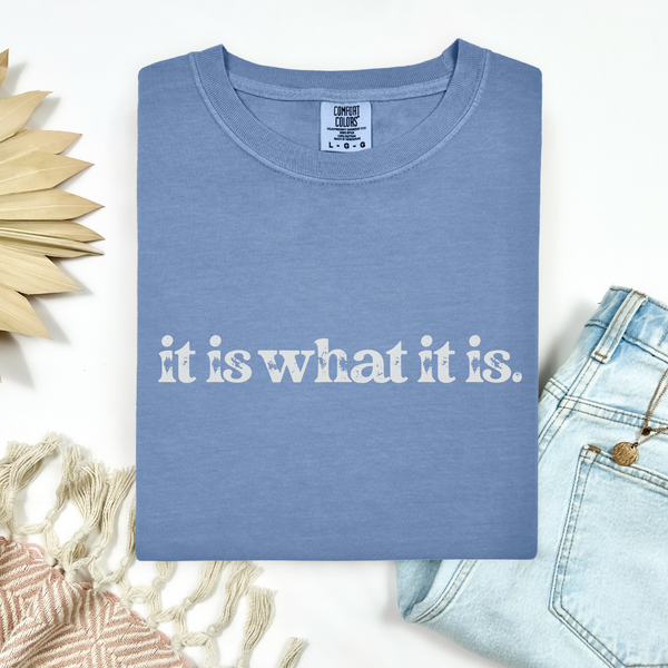 Blue t-shirt with 'it is what it is' text on a white background