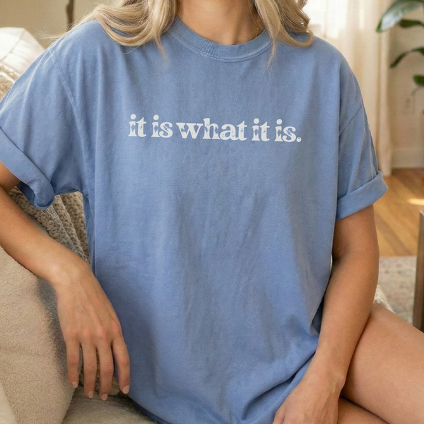 Person wearing a blue t-shirt with 'it is what it is' text.