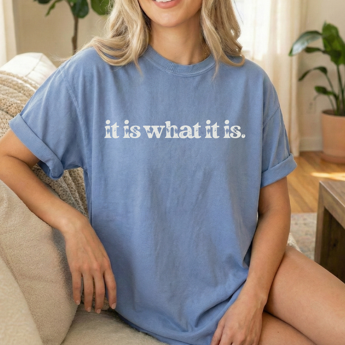 Person wearing a blue t-shirt with 'it is what it is' text in a casual setting.