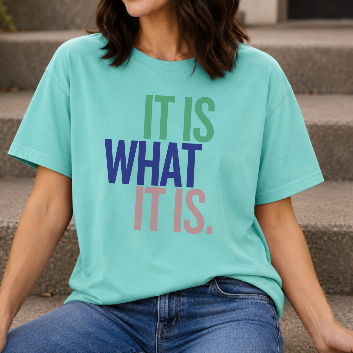 Person wearing a teal t-shirt with motivational text sitting on steps.