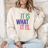 A woamn wearing a beige sweatshirt with colorful text that reads 