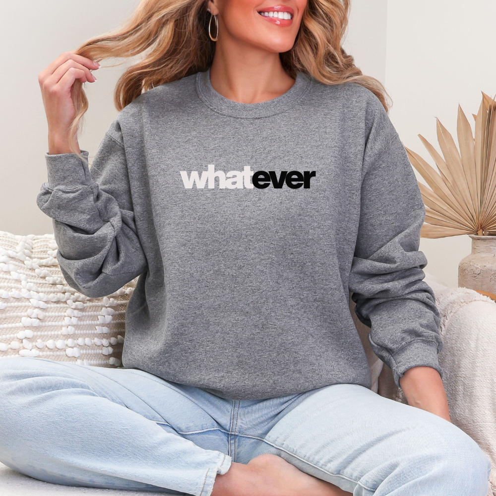 A woman wearing a gray sweatshirt with 'whatever' text, sitting on a couch.