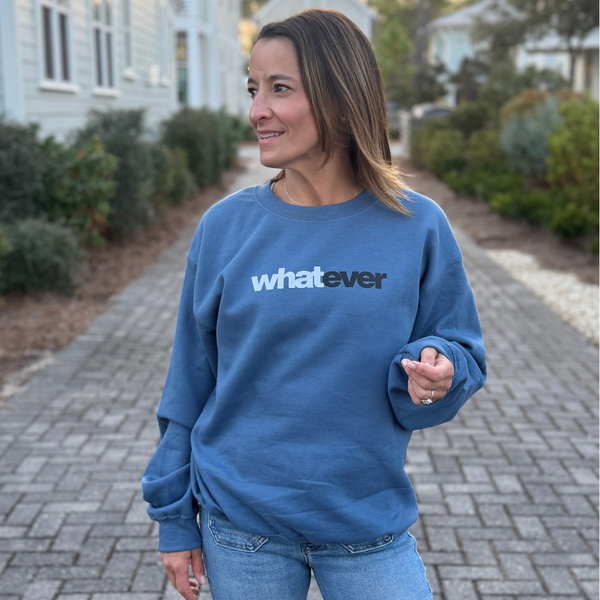 Woman wearing a blue sweatshirt with 'whatever' text on a paved path.