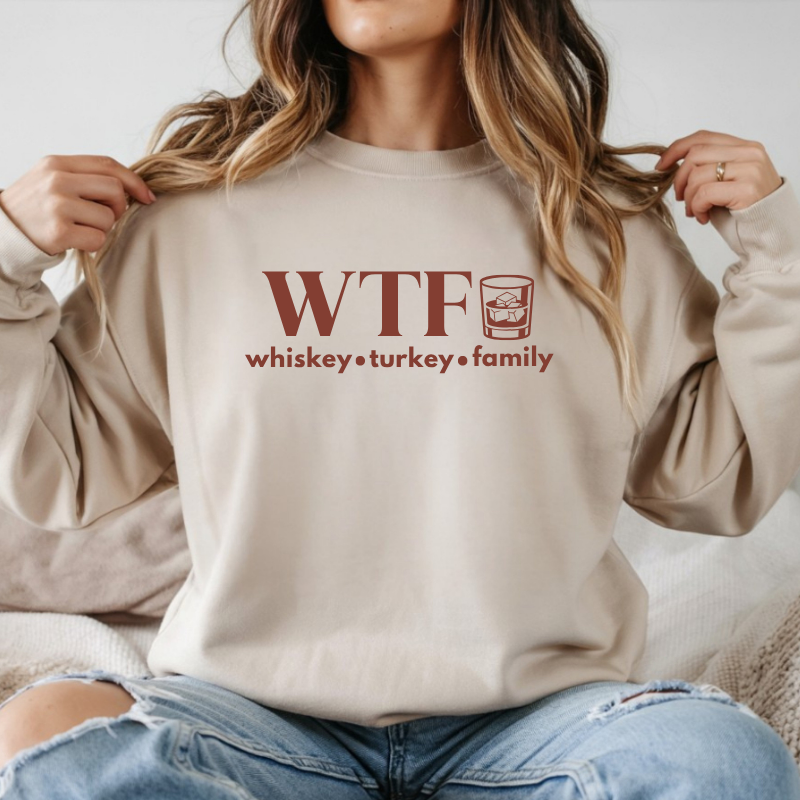 Person wearing a beige sweatshirt with 'WTF whiskey turkey family' text and graphic.