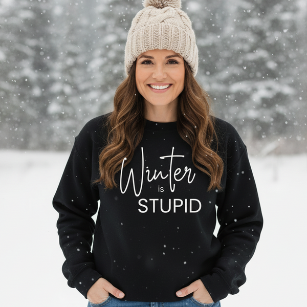 A woman in a Black Winter is Stupid sweatshirt in a snowy setting