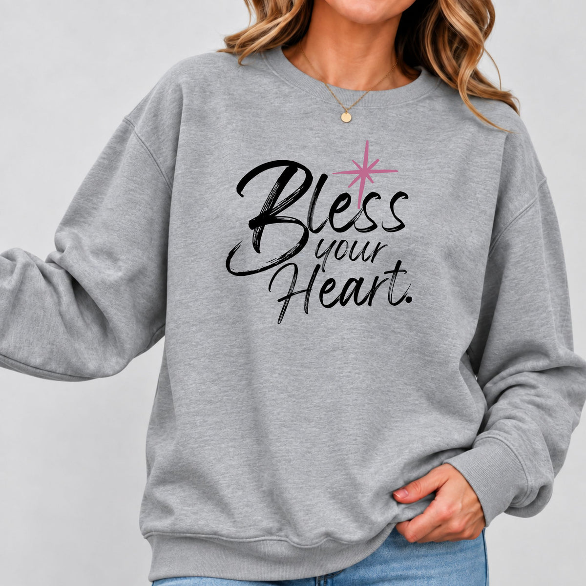 Woman wearing a gray Bless Your Heart sweatshirt with black script lettering and jeans