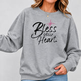 Woman wearing a gray Bless Your Heart sweatshirt with black script lettering and jeans