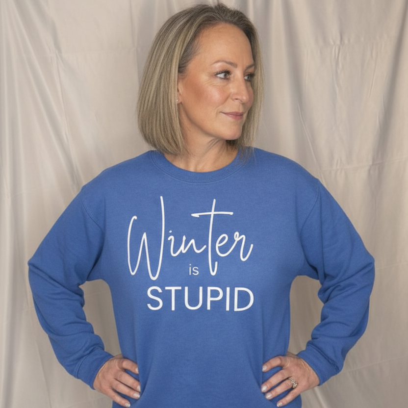 A woman wearing a blue sweatshirt with 'Winter is Stupid' text against a plain background
