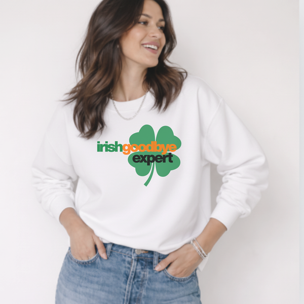 Woman wearing a white sweatshirt with a green shamrock design and text.