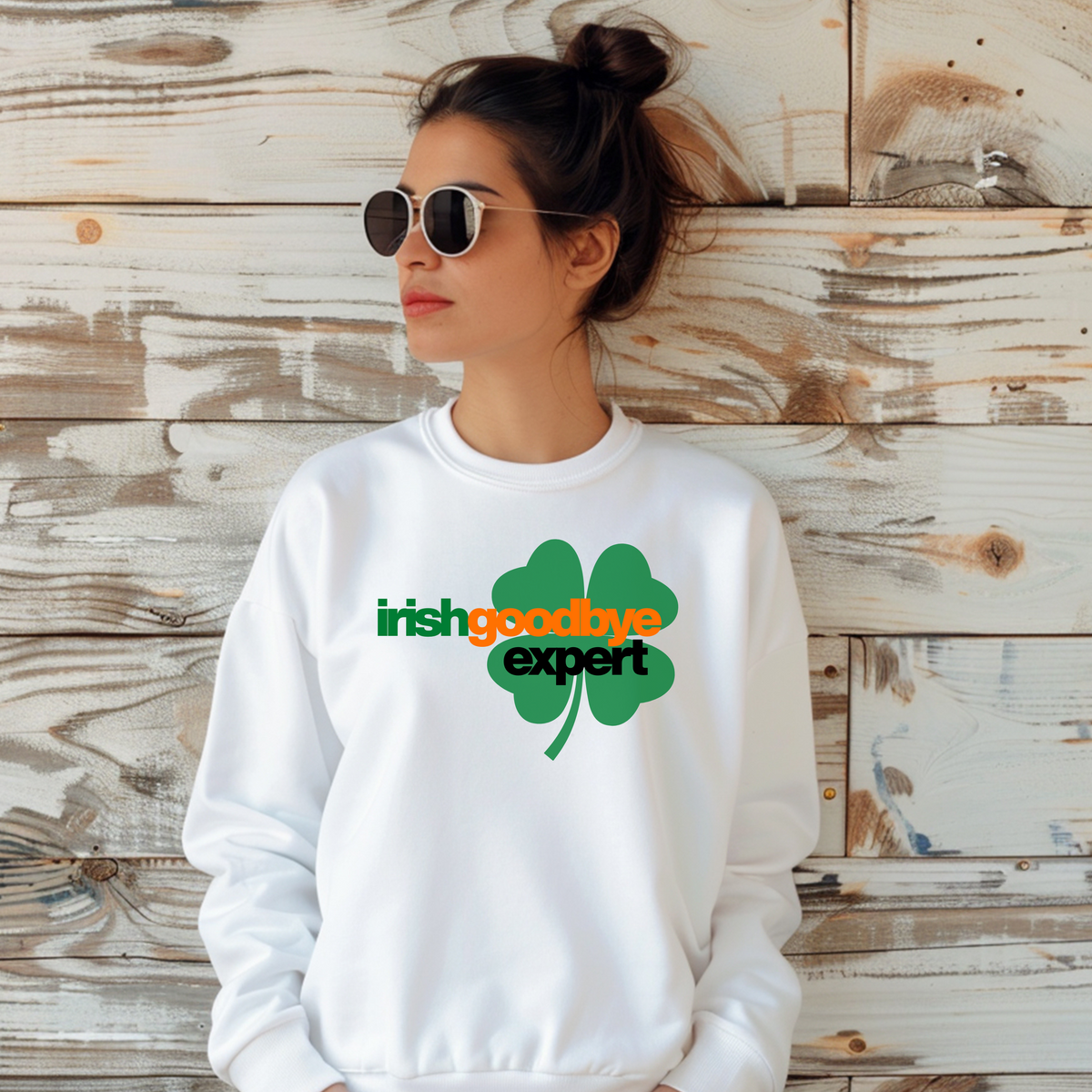 Woman wearing a white sweatshirt with a green four-leaf clover design and text against a wooden background