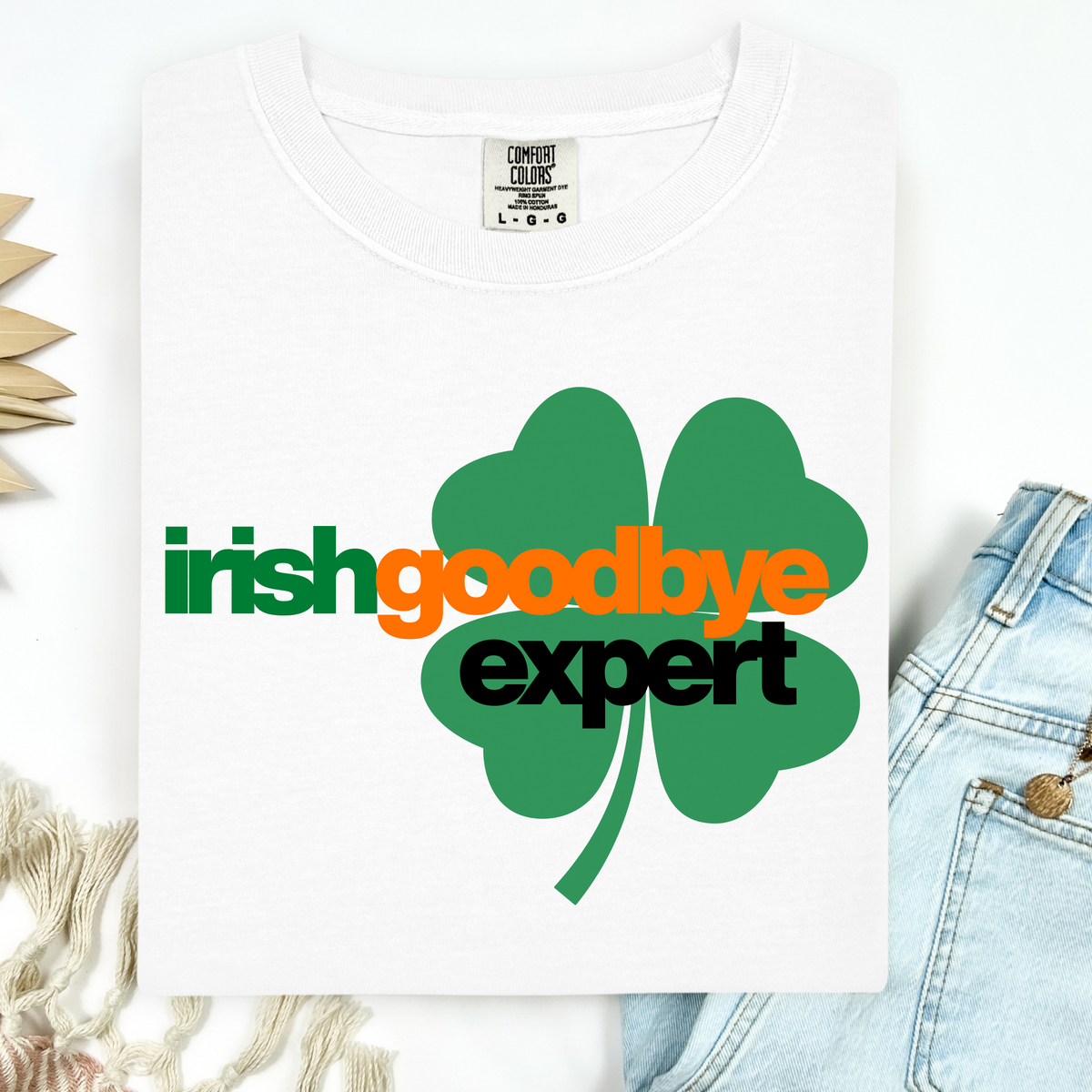 White t-shirt with a green four-leaf clover graphic and text 'irish goodbye expert' on a white background.