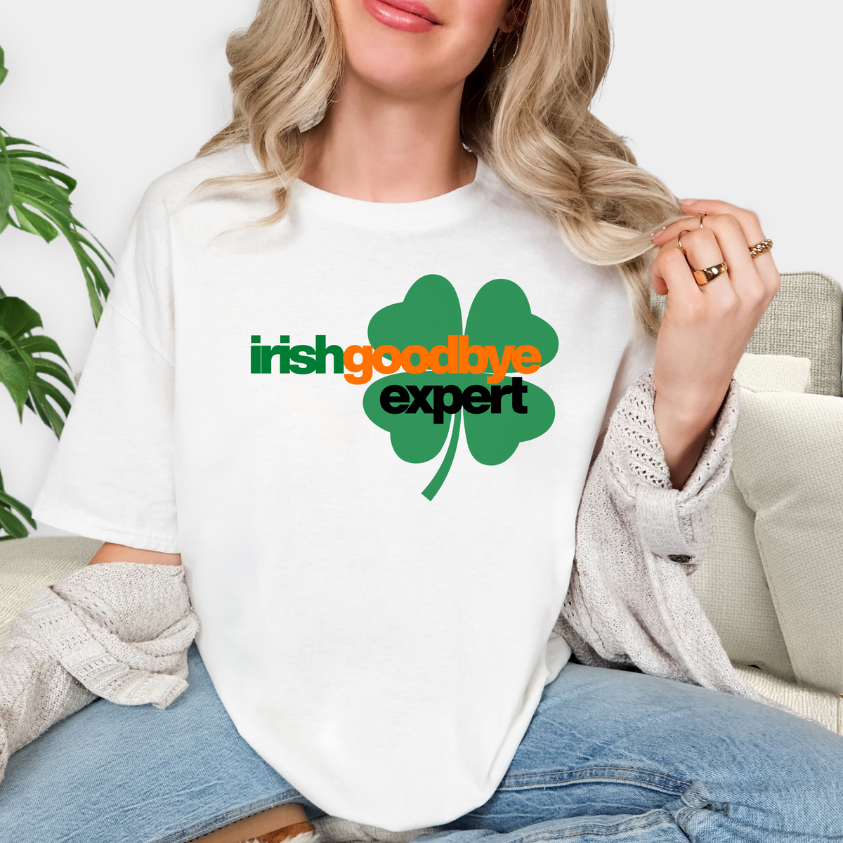 Person wearing a white t-shirt with 'irish goodbye expert' design, sitting on a couch.
