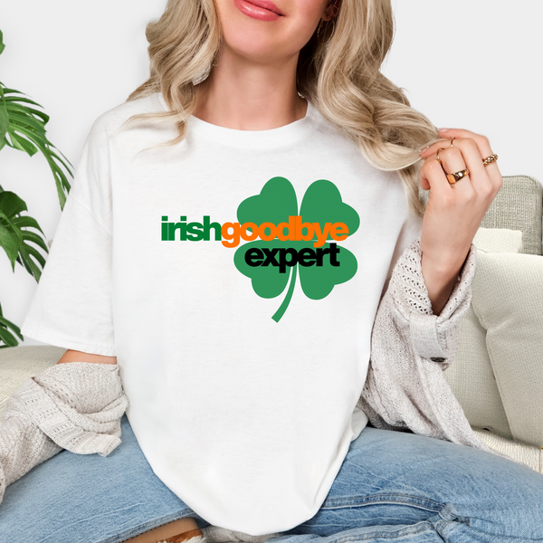 Person wearing a white t-shirt with 'irish goodbye expert' design, sitting on a couch.