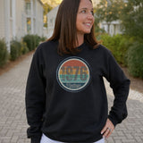 Woman wearing a black vintage birthday sweatshirt with a retro sunset birth year badge.